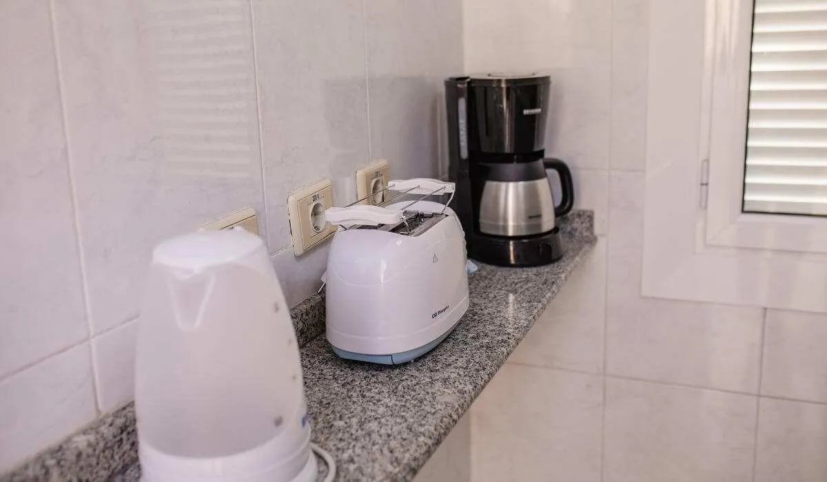 Electrodomésticos en la cocina: hervidor, tostadora y cafetera.
