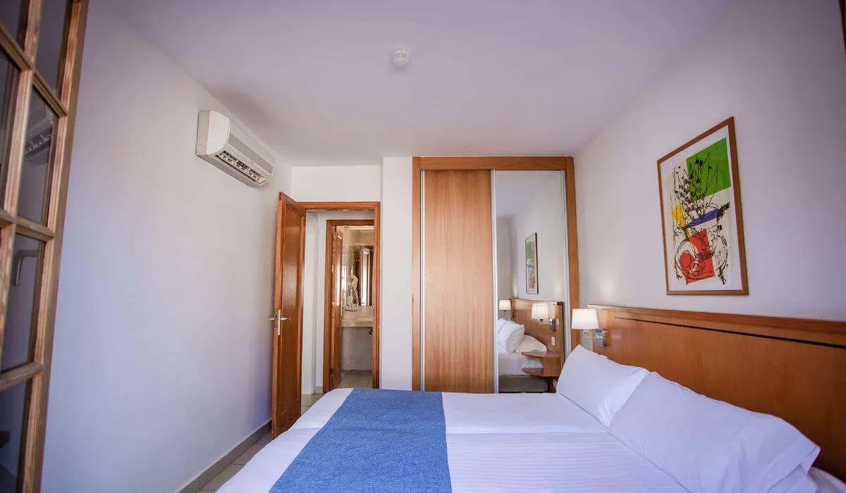 Habitación con cama doble, aire acondicionado y baño al fondo.