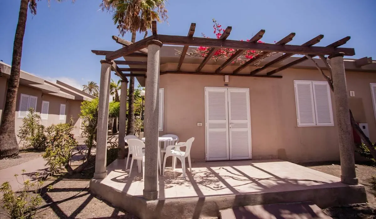Casa con pérgola, sillas y mesa en el jardín.