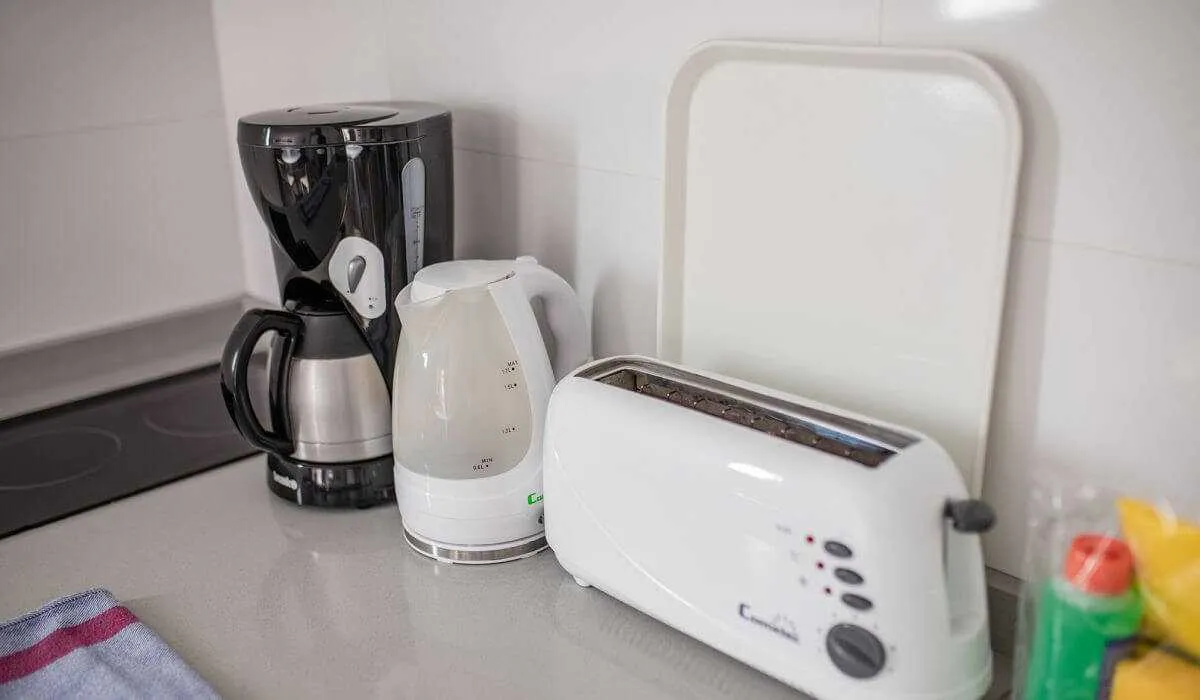 Cafetera, tetera y tostadora sobre un mostrador de cocina.