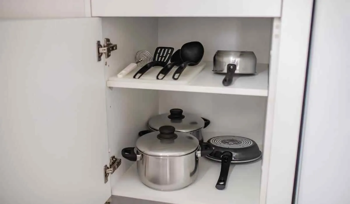 Utensilios y ollas organizados en un gabinete de cocina abierto.