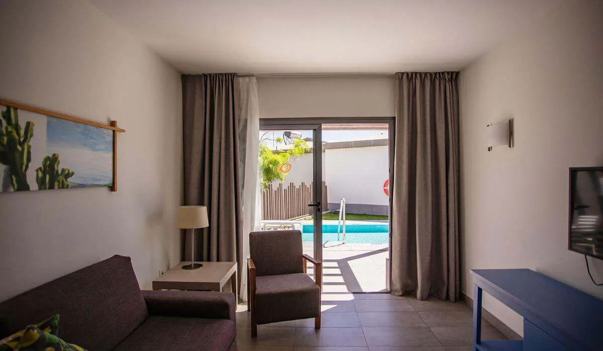 Sala con puerta de vidrio hacia una piscina y decoración sencilla.