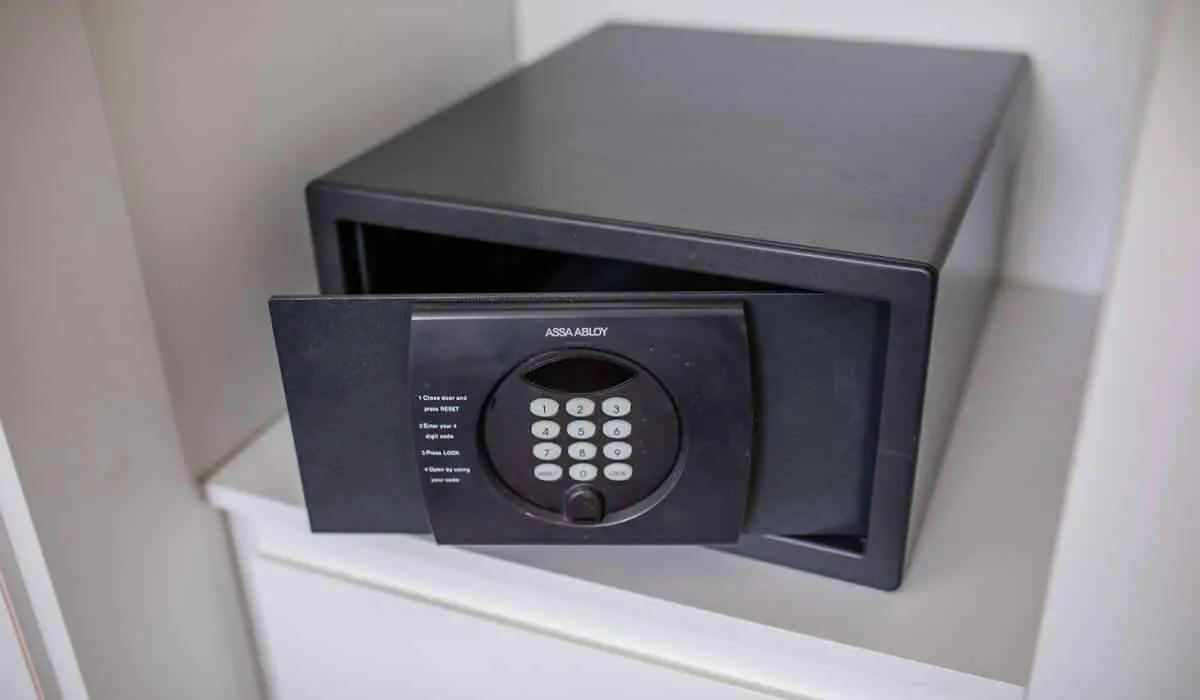 Caja fuerte negra con teclado numérico abierta sobre un estante blanco.