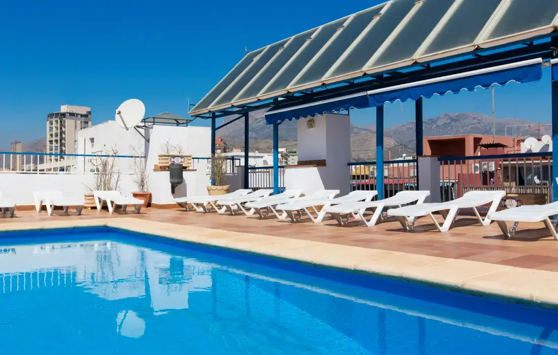 Piscina en una azotea con tumbonas y cielo despejado.
