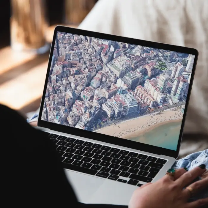Persona viendo una imagen a&eacute;rea de una ciudad en una laptop.