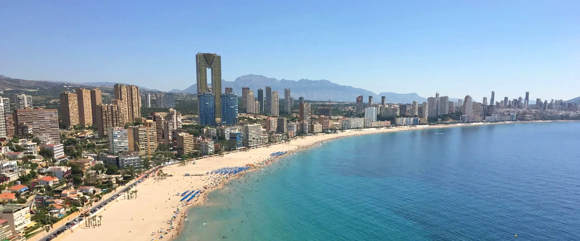 Playa y rascacielos de una ciudad costera bajo cielo despejado.