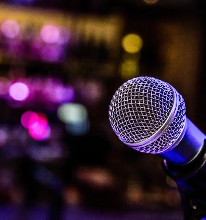 Primer plano de un micrófono con luces de colores difusas al fondo.