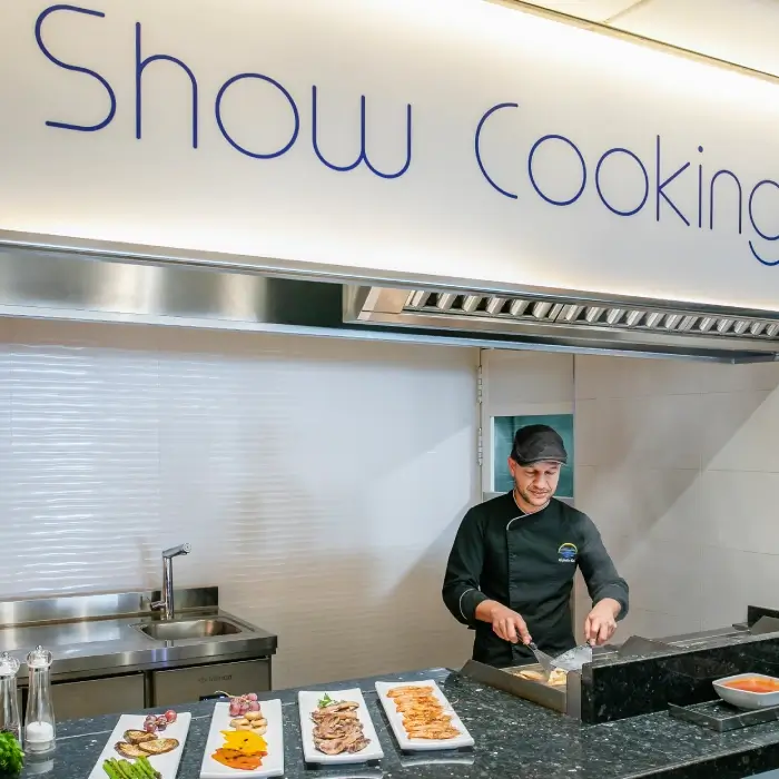 Chef cocinando en una estación de Show Cooking con platos variados frente a él.