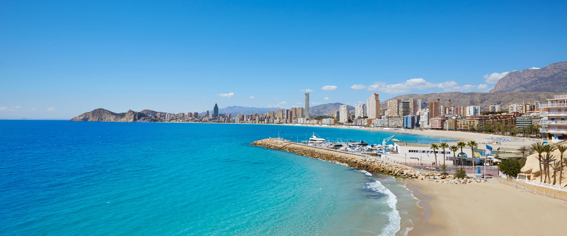 Vista de una playa urbana con edificios y un cielo despejado.