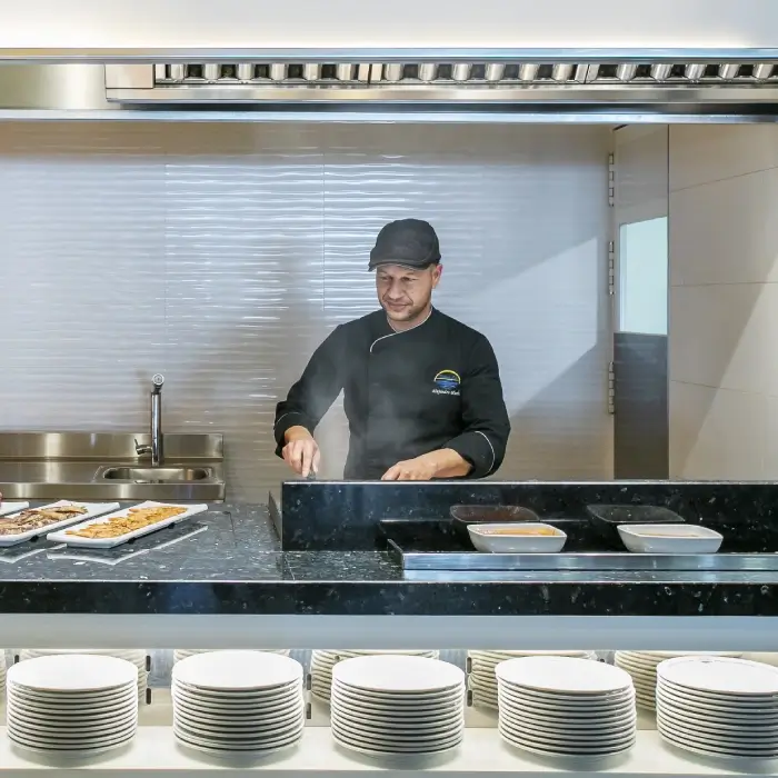 Chef cocinando en la parrilla de una cocina industrial moderna.