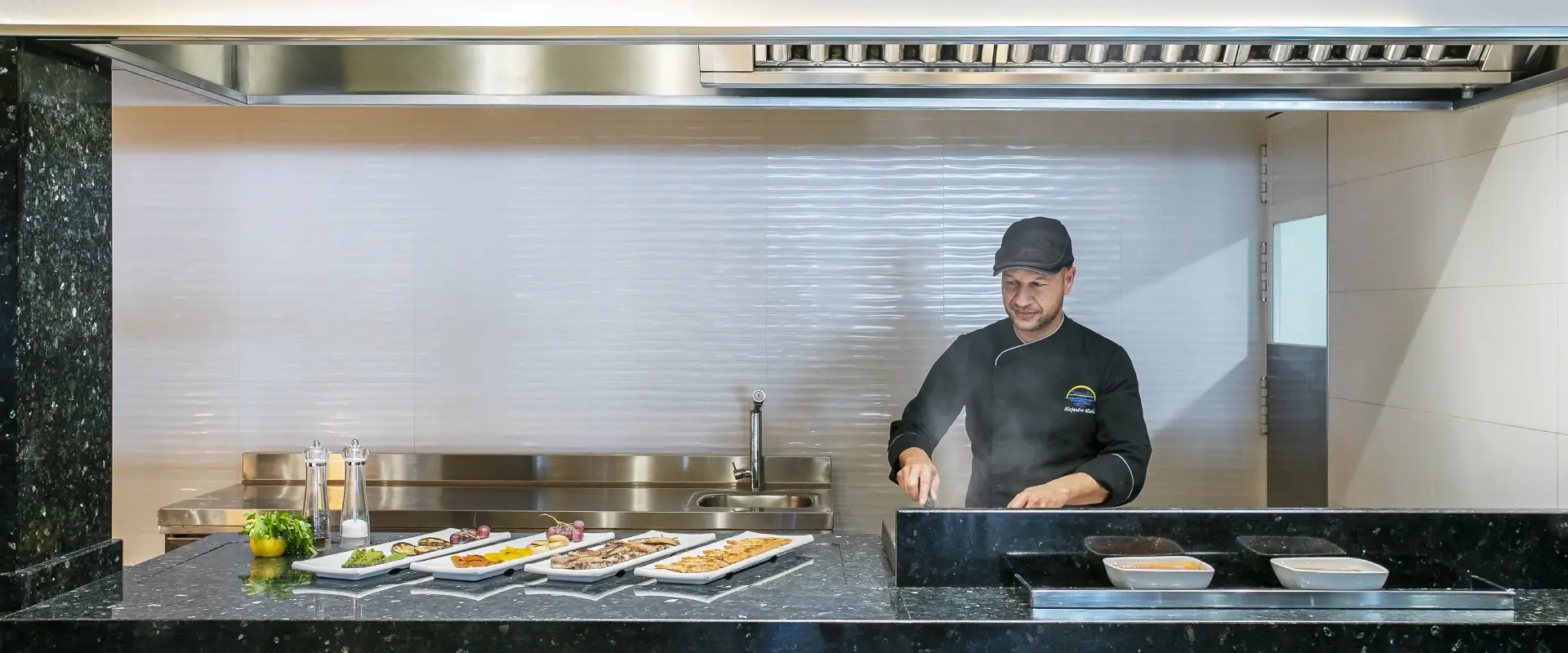 Chef cocinando en una plancha con platos preparados enfrente.