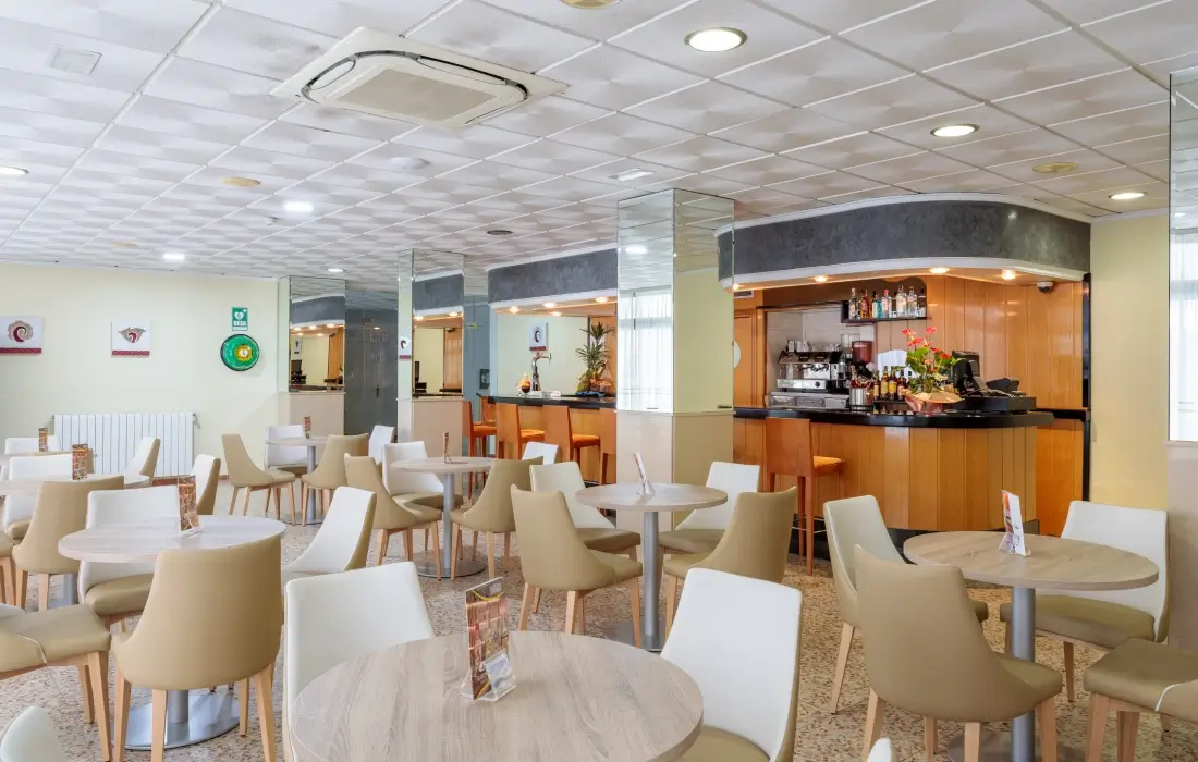 Cafetería luminosa con mesas redondas y sillas modernas.