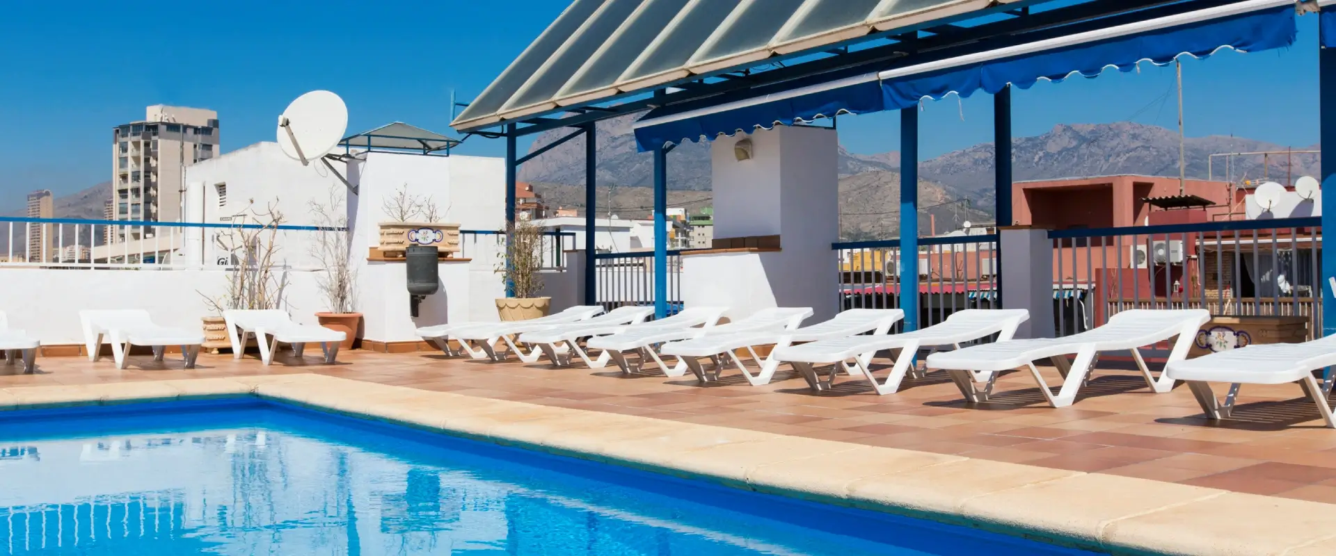 Terraza con piscina y tumbonas bajo un cielo despejado.
