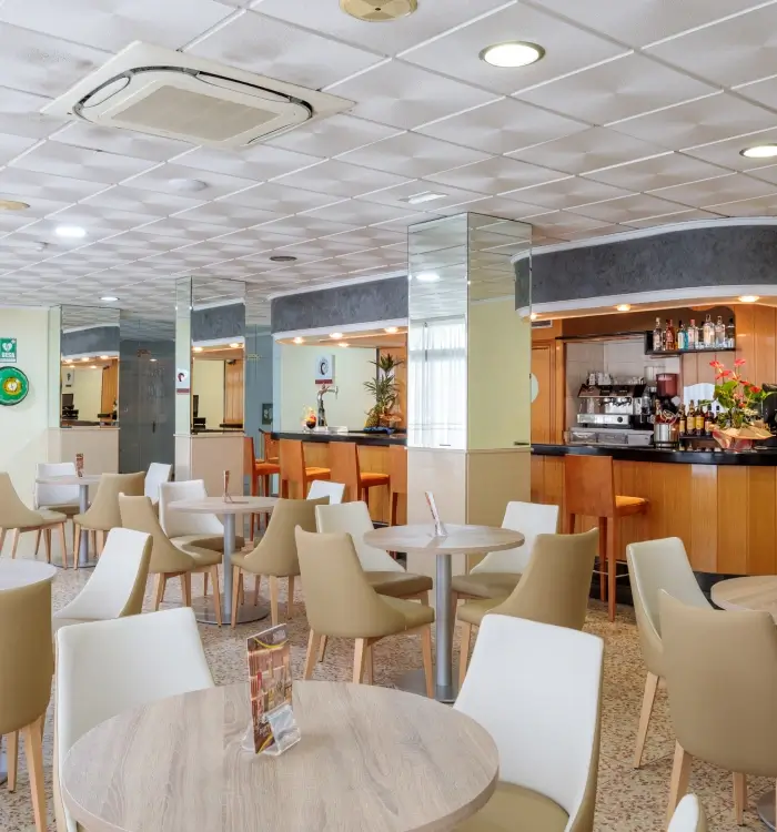 Cafetería moderna con mesas, sillas y barra bien equipada.