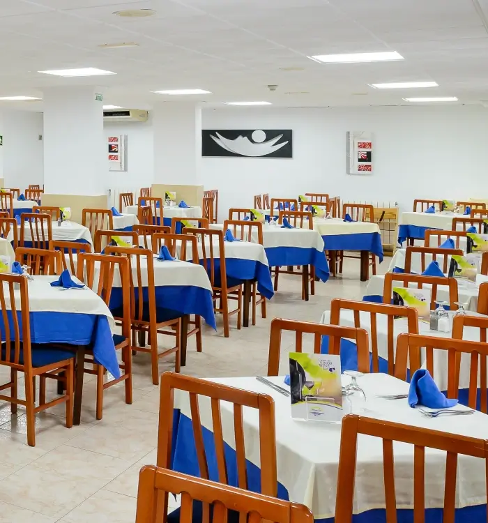Comedor con mesas cubiertas con manteles azules y sillas de madera.