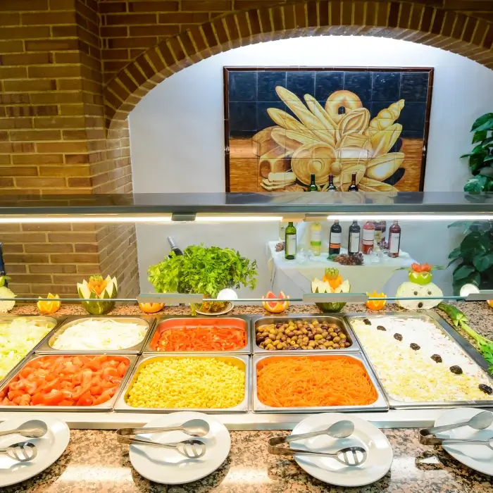 Buffet de ensaladas con variedad de ingredientes y decoraciones florales.