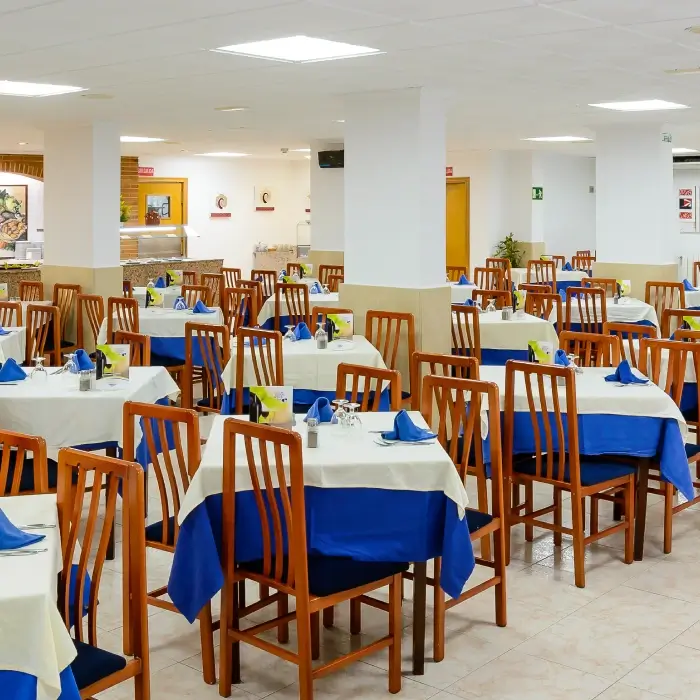 Restaurante con mesas cubiertas con manteles azules y sillas de madera.