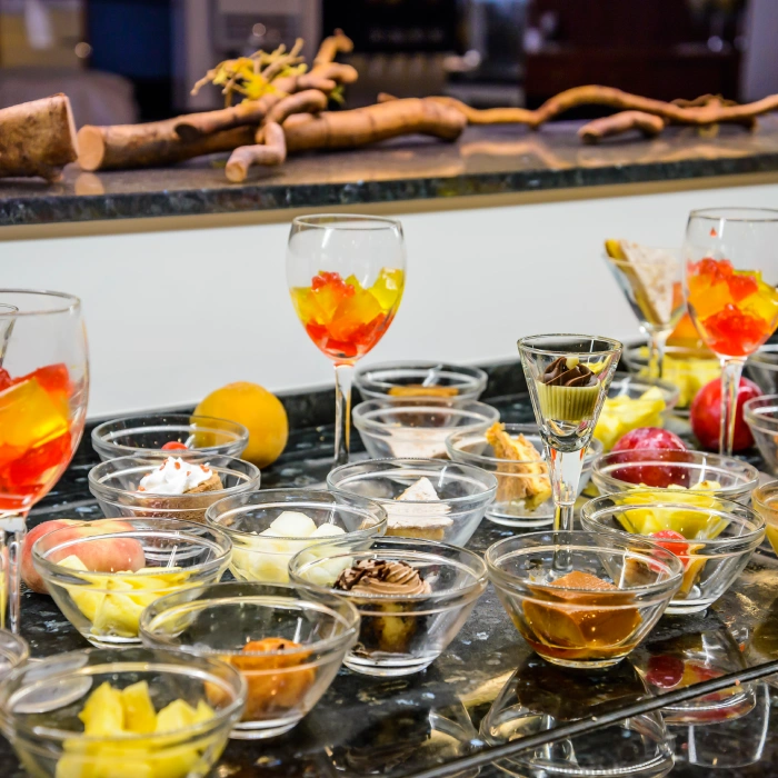 Postres variados en copas y cuencos sobre una mesa negra decorada.