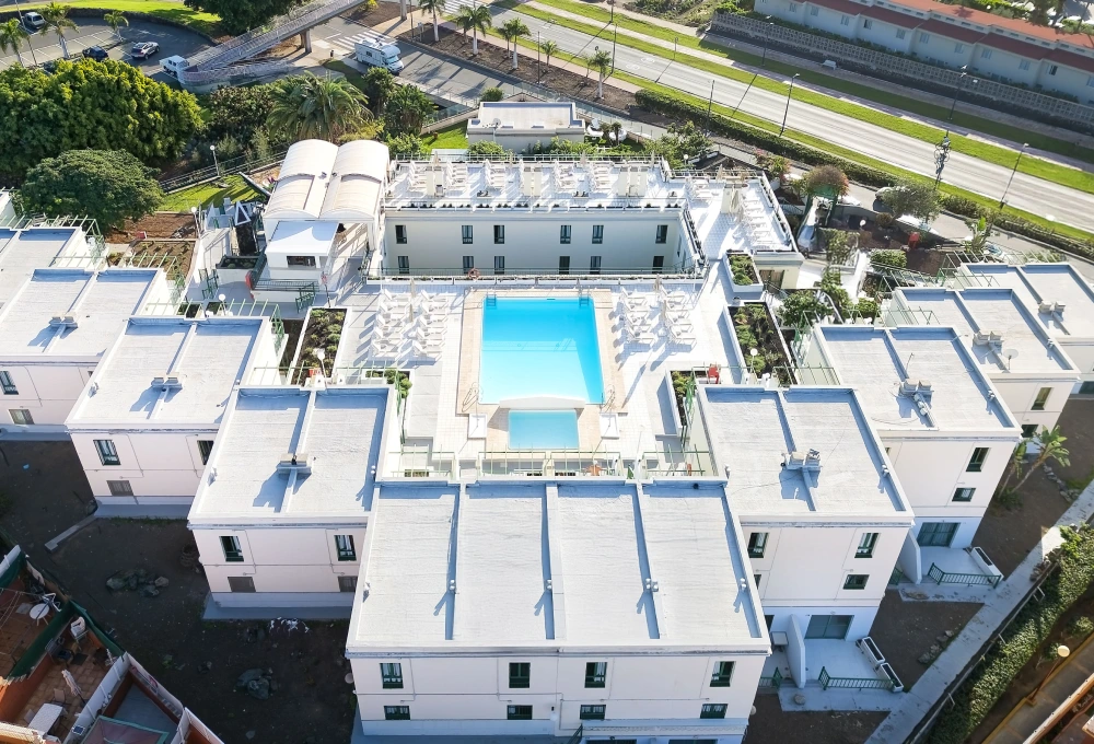 Vista a&eacute;rea de un complejo de edificios con piscina central y jardines alrededor.