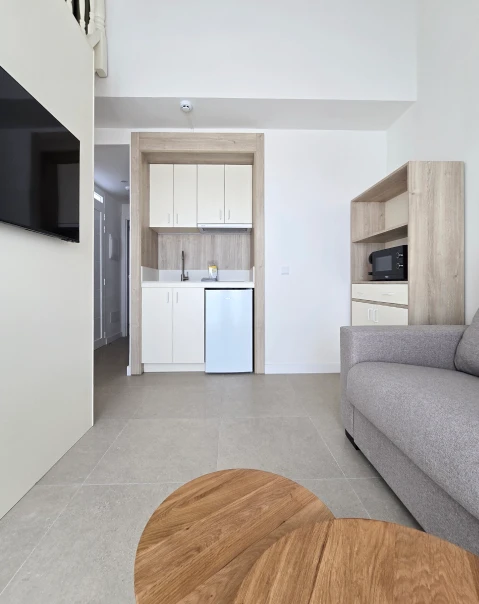 Sala moderna con cocina compacta, sofá, TV y microondas.
