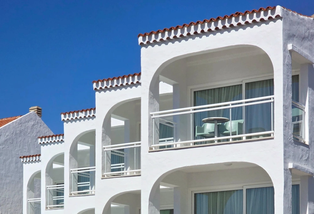 Edificio moderno con balcones y cielo azul claro.