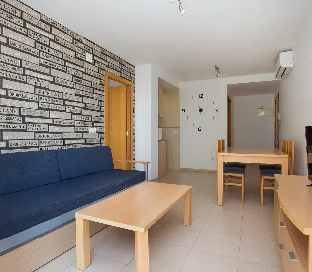 Sala moderna con sofá azul, mesa de madera, pared decorativa y reloj grande en la pared.