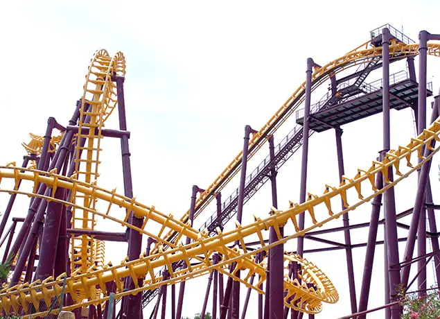 Montaña rusa amarilla y morada con rieles en espiral y estructura metálica alta.