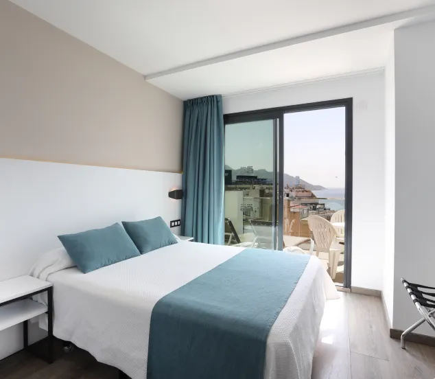 Habitación moderna con cama doble, balcón y vista al mar.