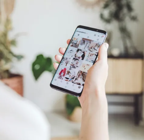 Persona sosteniendo un smartphone con una aplicación de redes sociales abierta en la pantalla.