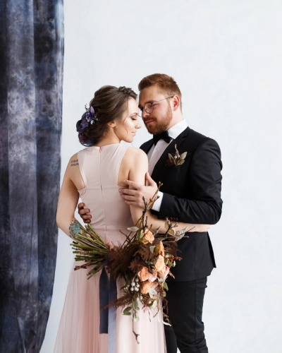 Couple embracing, woman holding a bouquet, in formal attire.