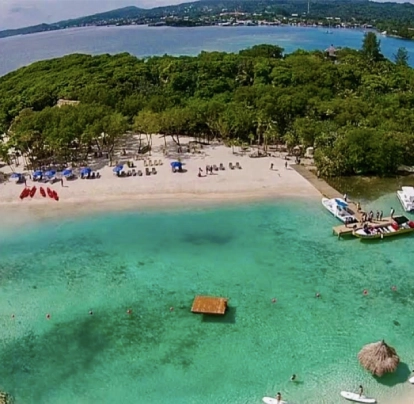 Playa con agua turquesa, arena blanca y vegetación en la costa.
