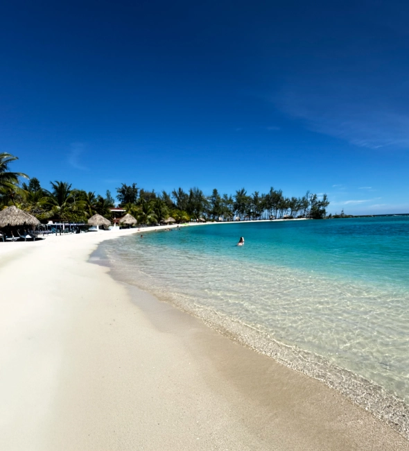 Playa paradisíaca con aguas turquesas y arena blanca bajo un cielo despejado.