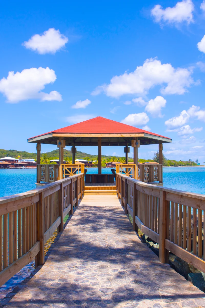 Wooden gazebo over water with clear blue sky.