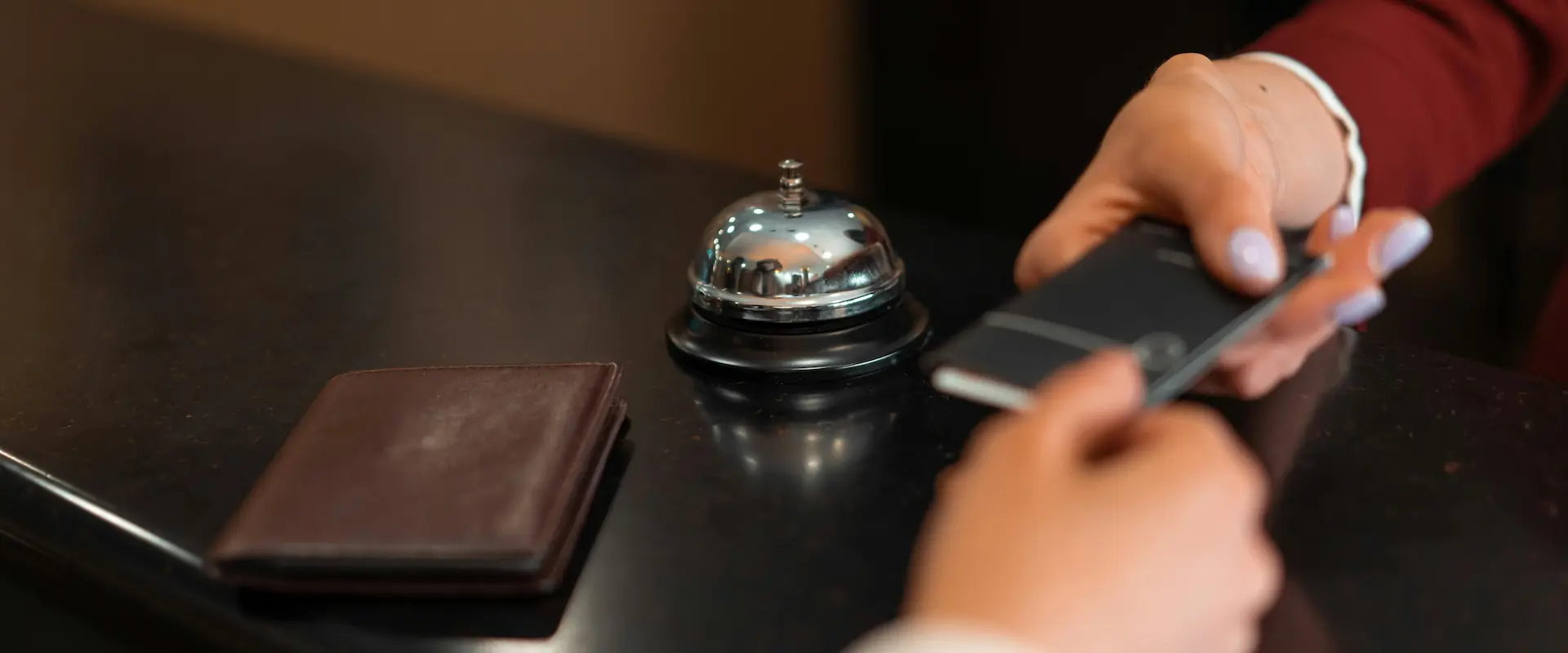 Main posant un passeport à côté d'une sonnette sur un comptoir de réception.