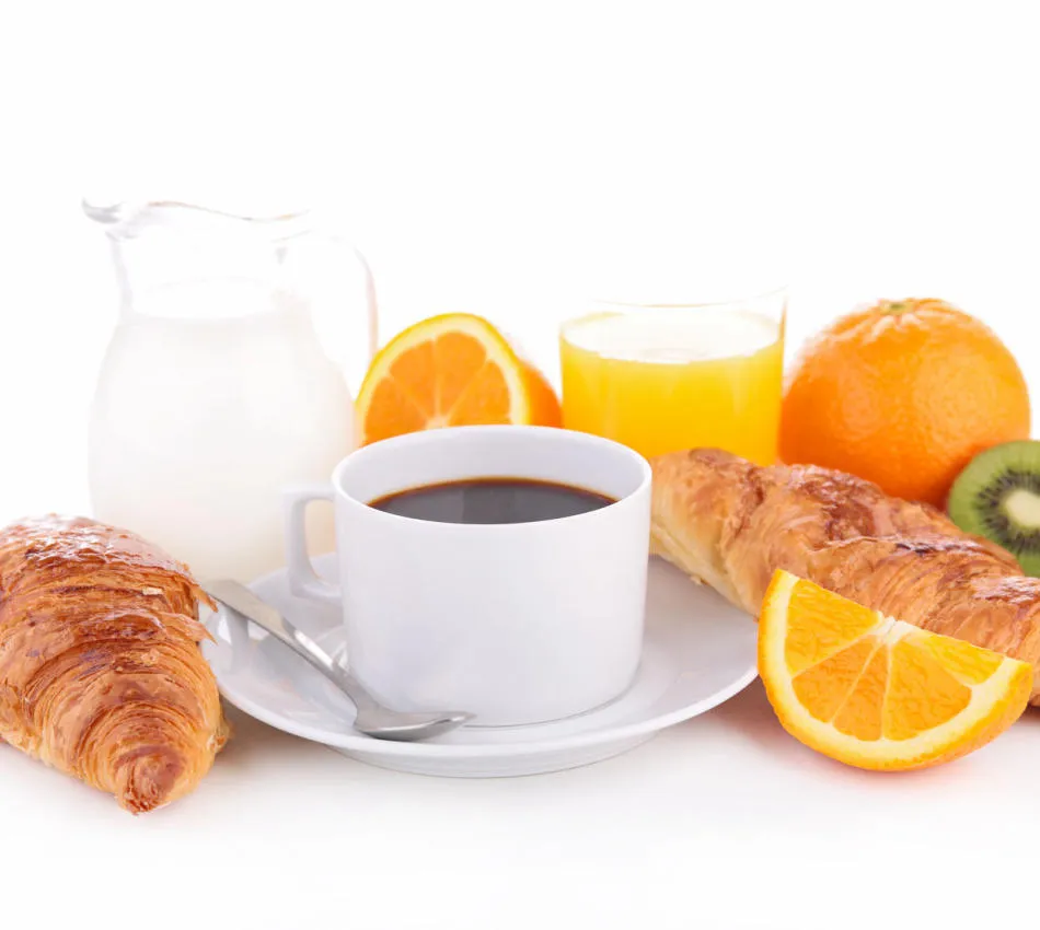 Petit-déjeuner avec café, croissants, orange, kiwi, jus d'orange et lait sur fond blanc.