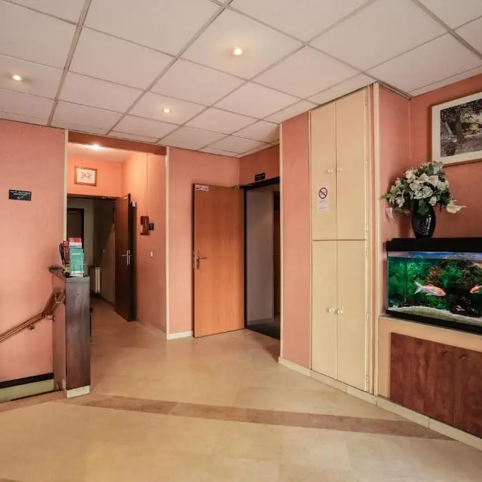 Couloir intérieur avec mur rose, aquarium, plantes et portes ouvertes.