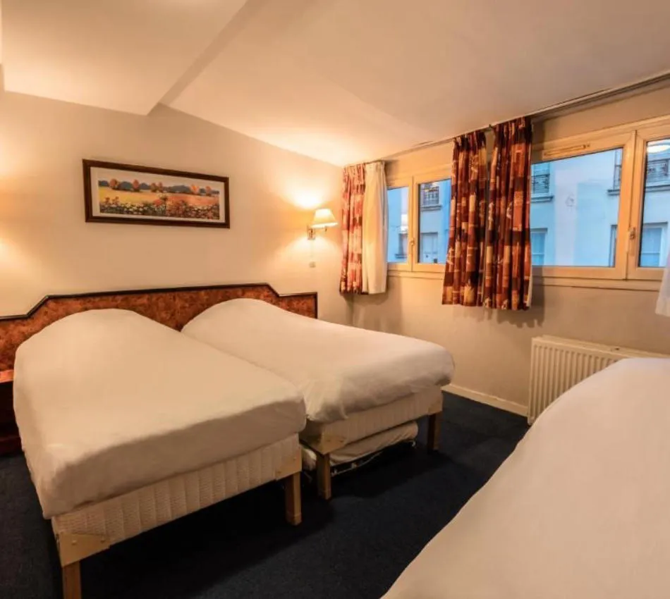 Chambre d'hôtel avec trois lits simples et décor simple, éclairée par des lampes murales.