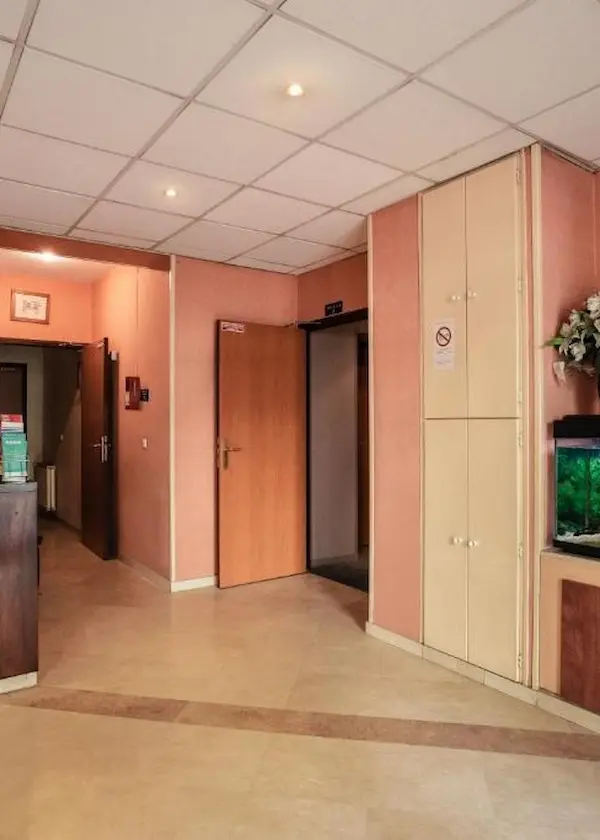 Intérieur d’un couloir avec portes ouvertes, murs roses et un aquarium à droite.