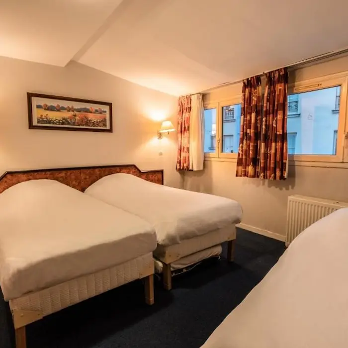 Chambre simple avec trois lits, fenêtres avec rideaux et éclairage doux.