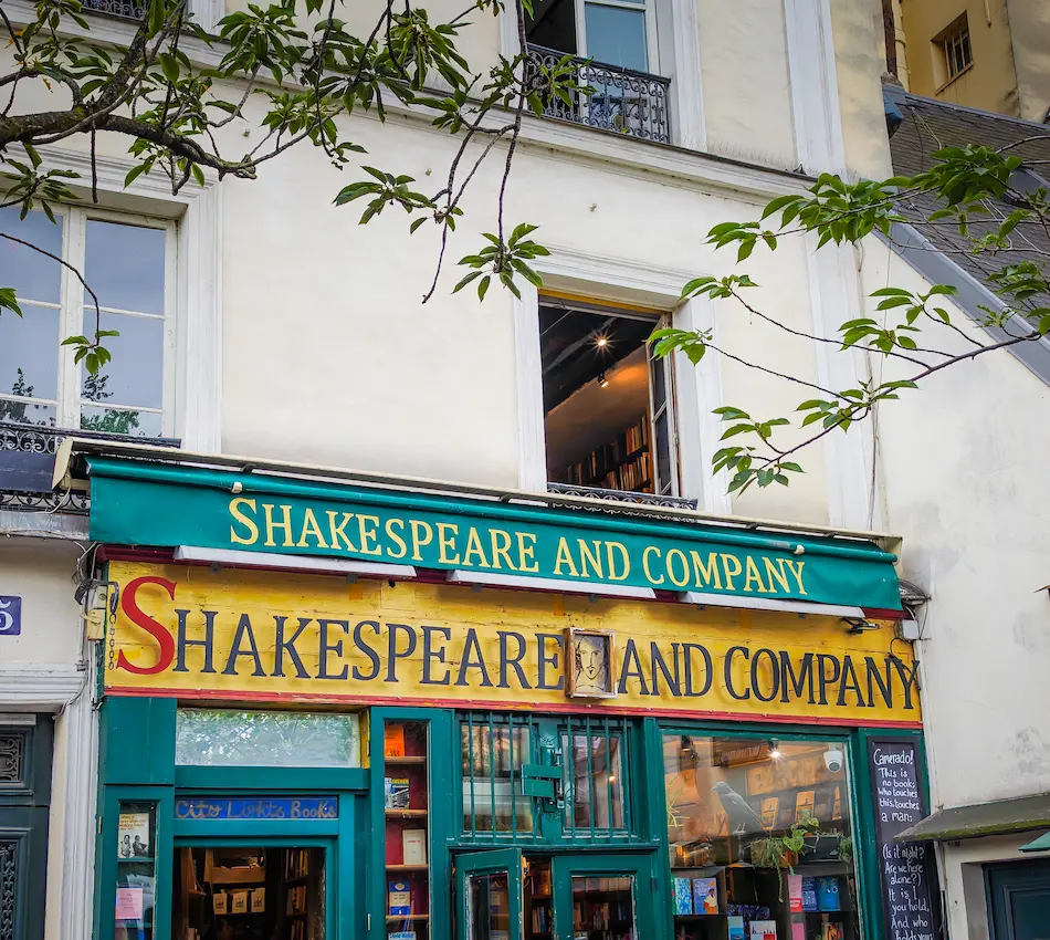 Façade de la librairie Shakespeare and Company à Paris, avec des livres visibles à l'intérieur.