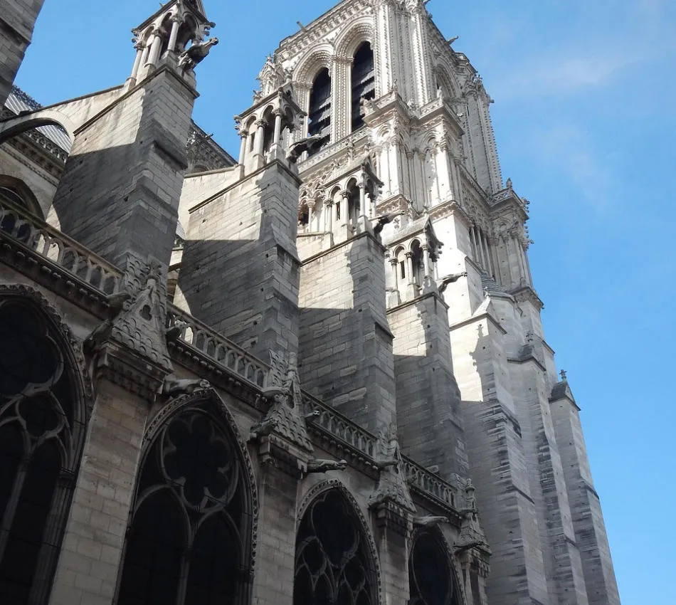 Cathédrale gothique avec arcs-boutants et ciel bleu en arrière-plan.