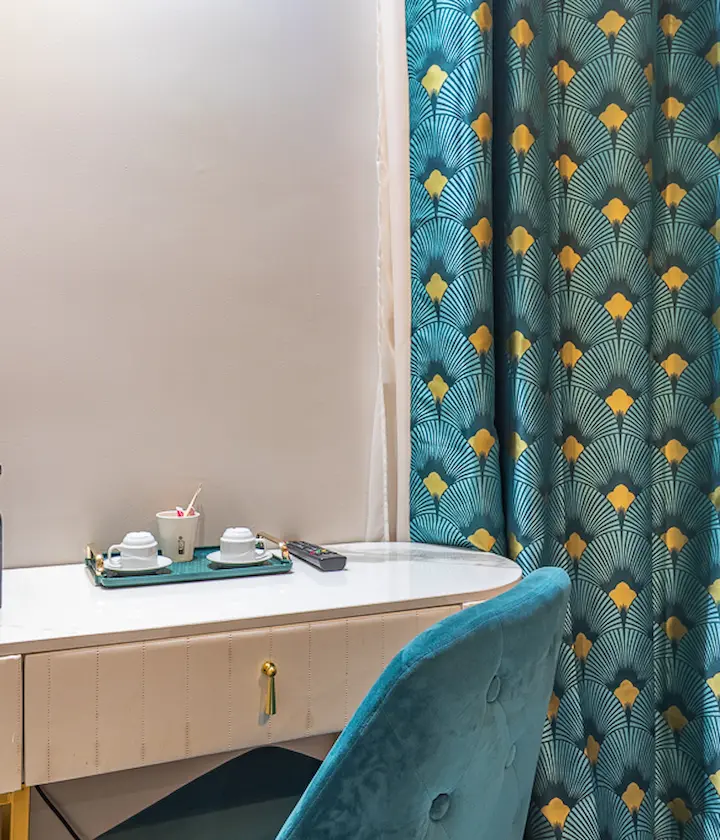 Bureau avec rideaux à motifs, tasse et plateau sur le côté.