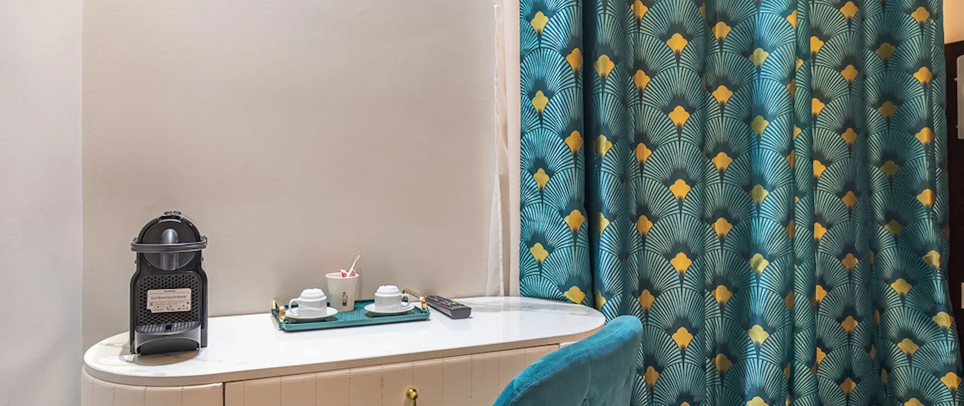 Machine à café sur buffet avec rideaux bleus à motifs géométriques.