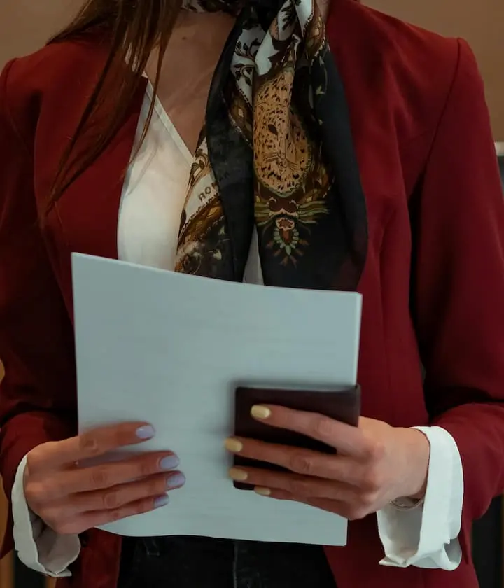 Une femme en foulard tient un dossier et un portefeuille.