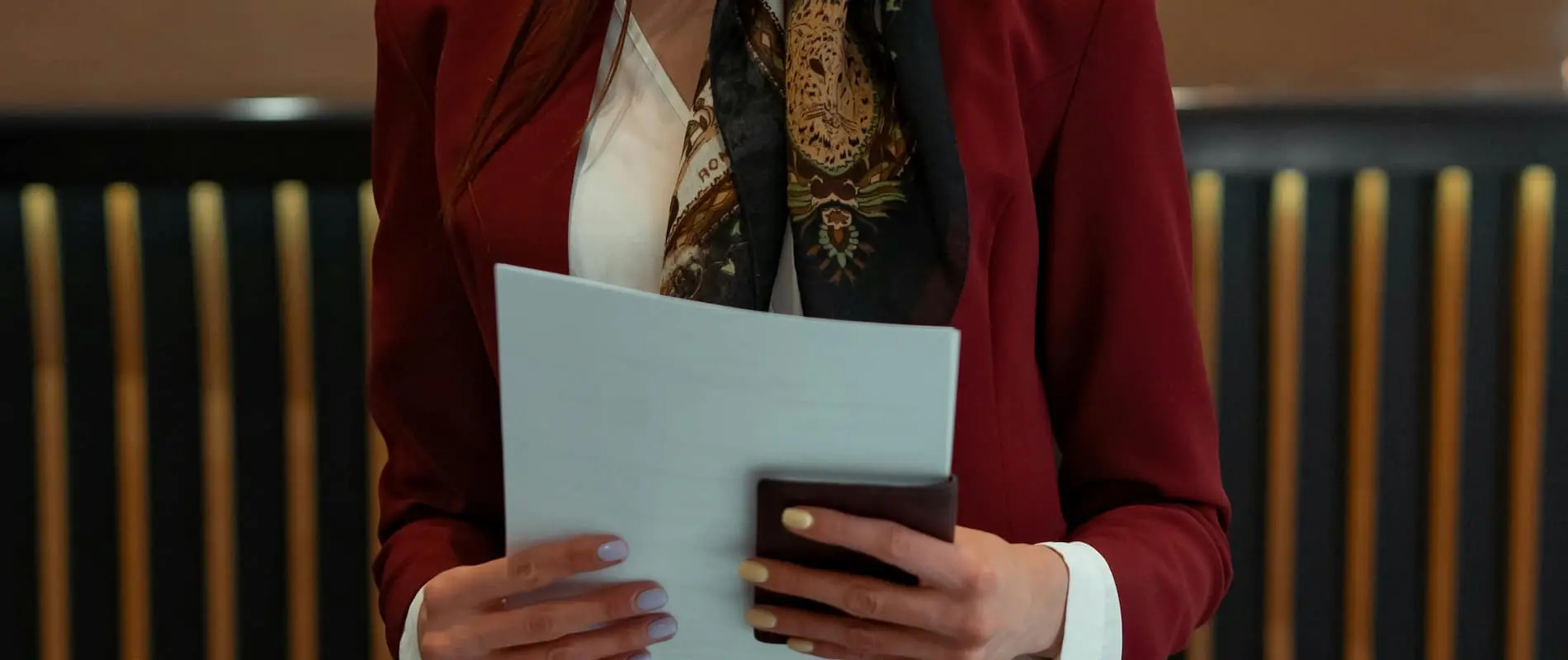 Personne en veste rouge tenant des documents et un portefeuille.