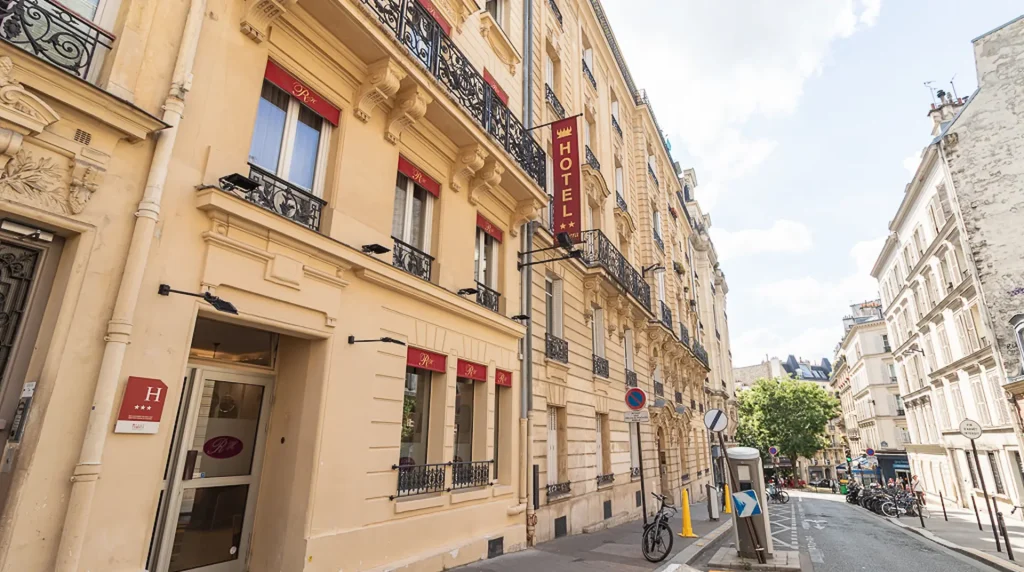 Rue parisienne avec un h&ocirc;tel et une rang&eacute;e de b&acirc;timents historiques.