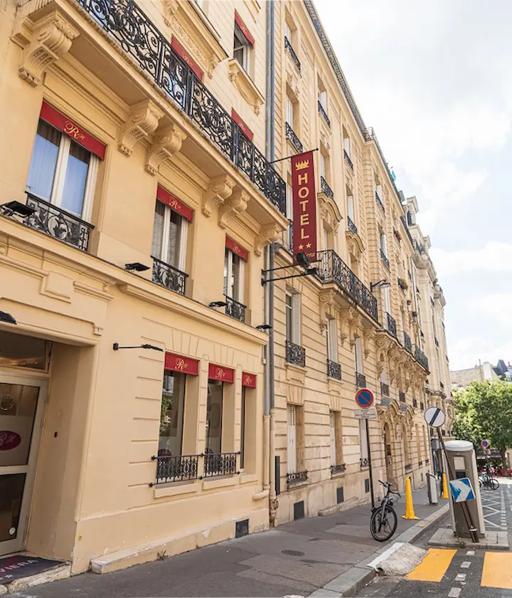 Façade de l'hôtel à deux étoiles avec balcons en fer forgé et vélo sur le trottoir.