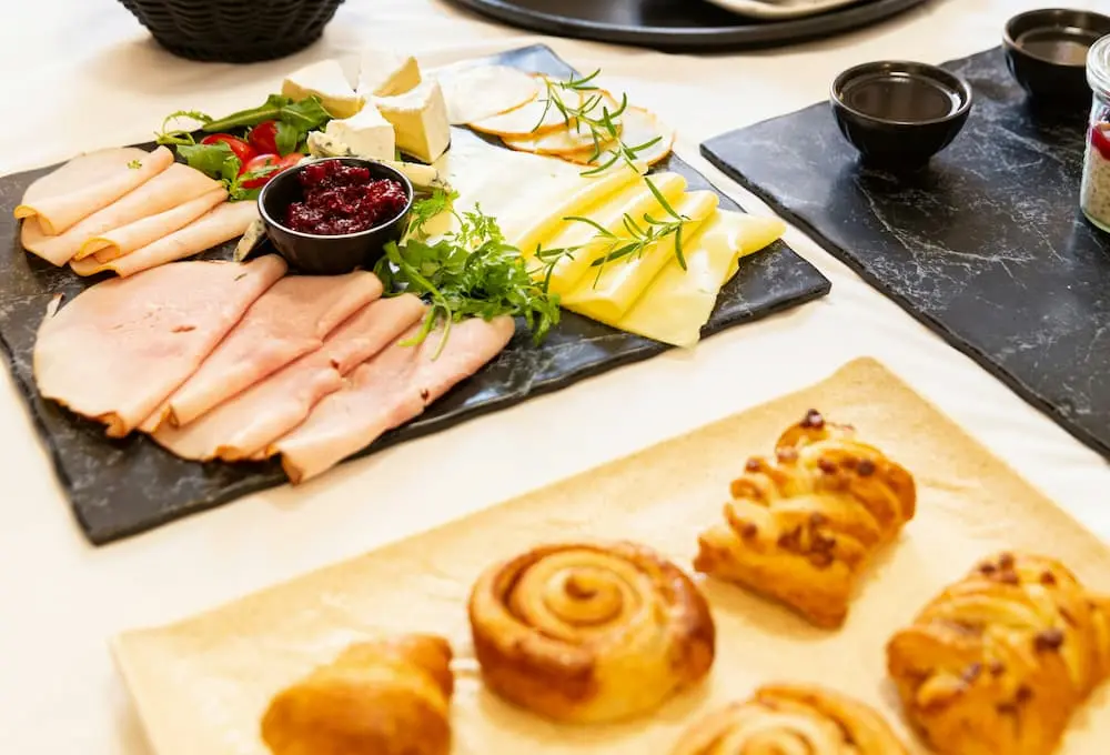 Plateau de charcuterie, fromage et viennoiseries sur une table.