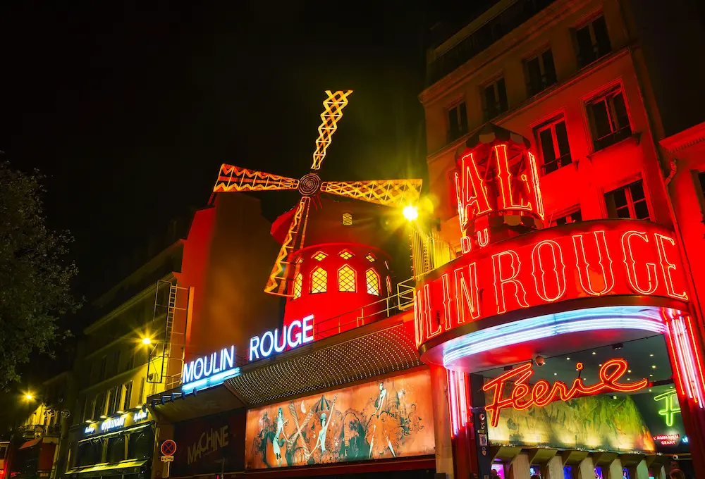 Moulin Rouge illuminé la nuit avec ses enseignes néon rouges.