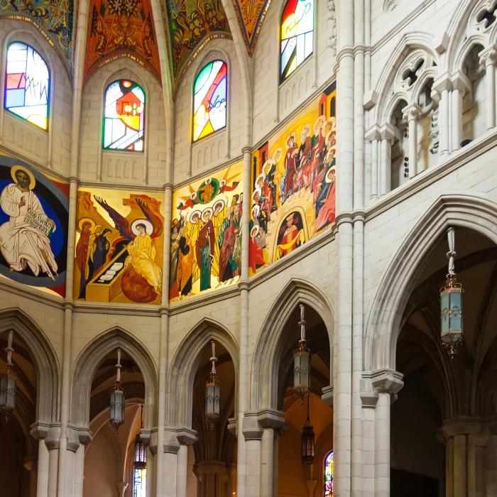 Intérieur d'une église avec des mosaïques colorées et des vitraux illuminés.